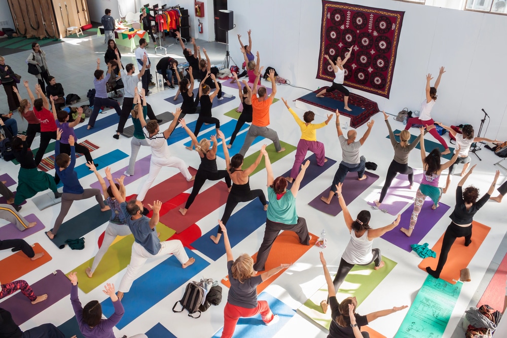 Large group of people practicing yoga in a museum.